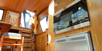 vesta-zicht-op-de-salon-met-koelkast-en-magnetron-op-de-voorgrond-aan-boord-van-jacht-de-Vesta-van-Yachts4U-jachtverhuur.jpg